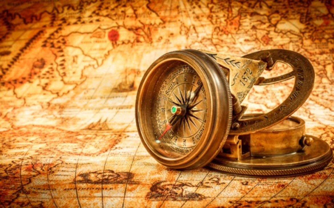 Vintage compass lies on an ancient world map.